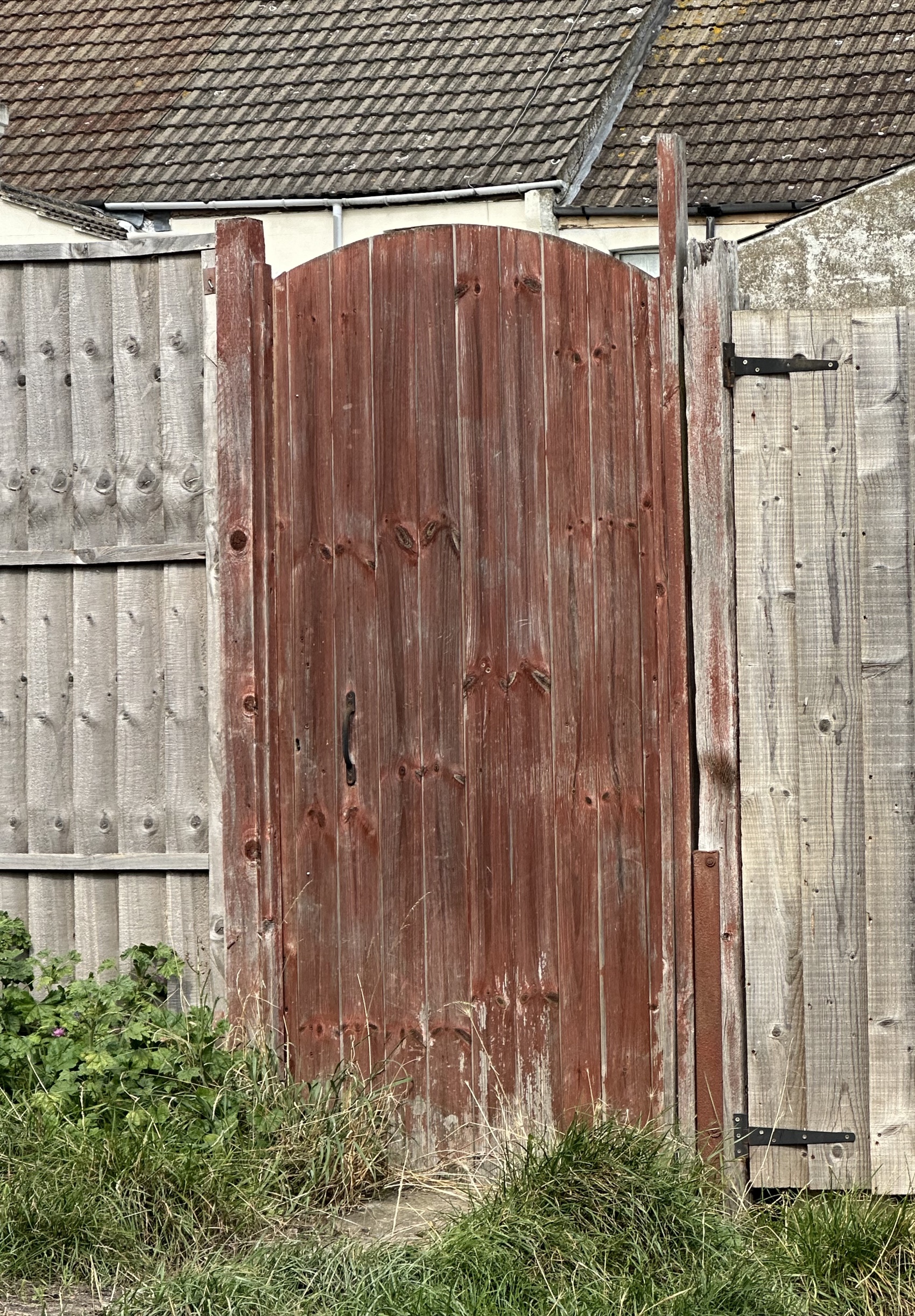 portail en bois grisé et décoloré par la pluie et le soleil, installé contre une clôture