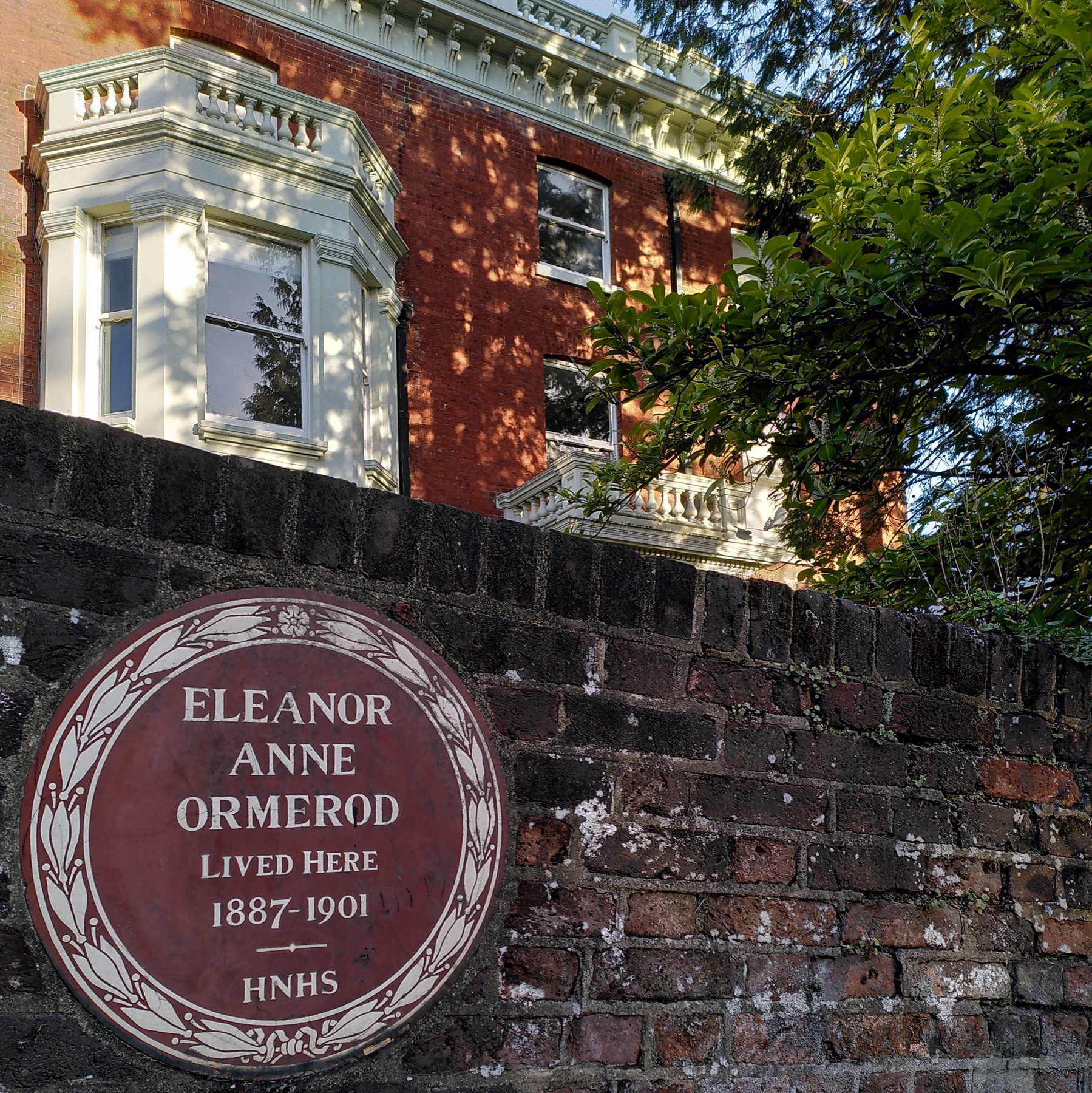 plaque ronde fixée sur un mur extérieur en briques, à côté d'une fenêtre
